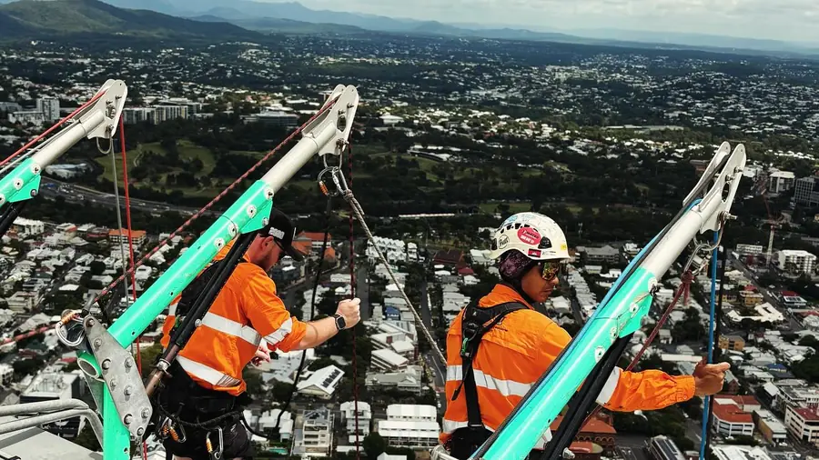 Rope access crew setting up rooftop davit rigging before work begins