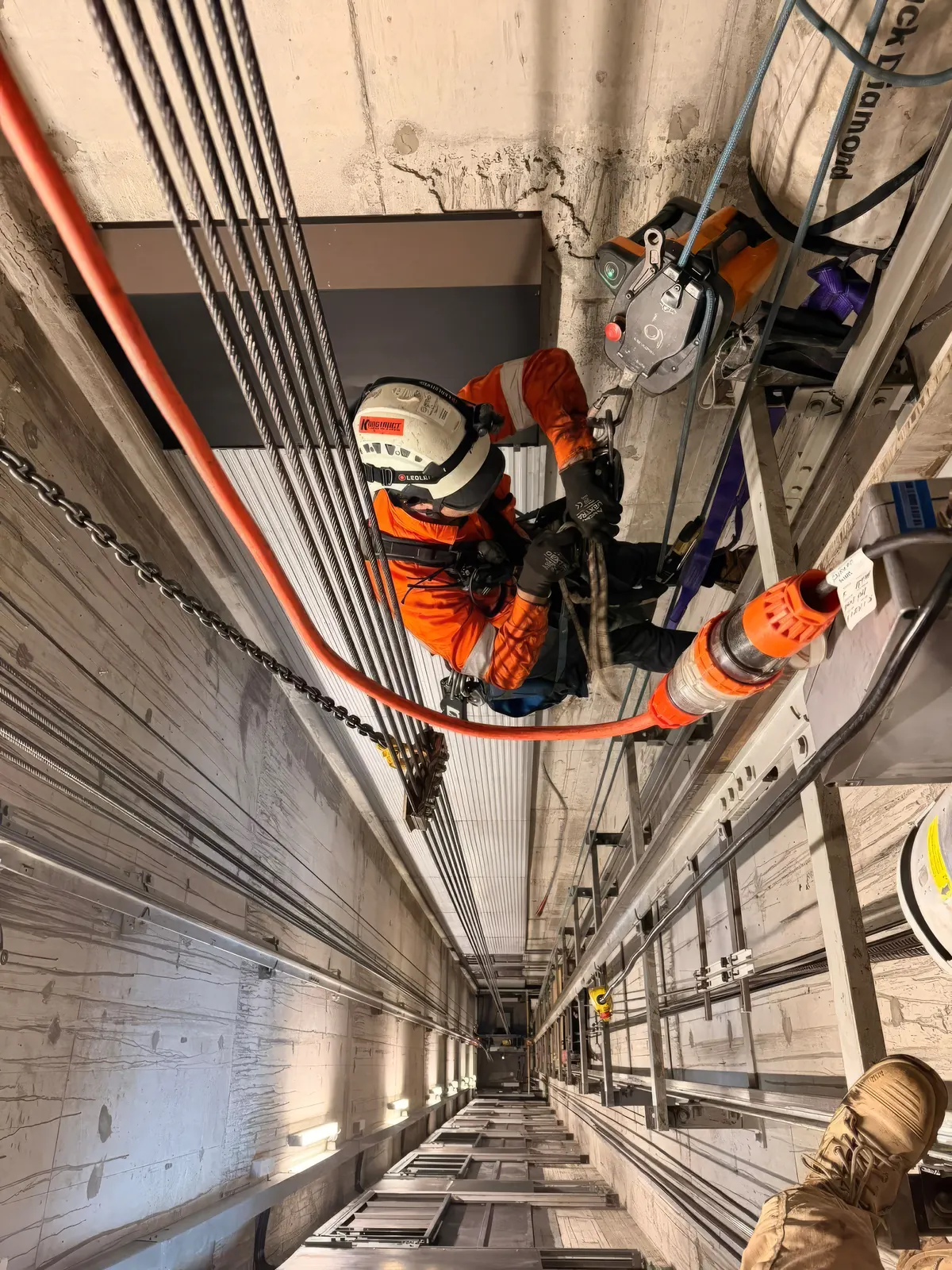 Konstruct technician rigging on rope inside a lift shaft, a chain block supporting the load above the shaft